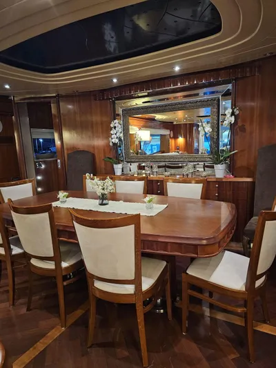 Naughty By Nature Yacht Photos Pics Luxurious dining area on a 2002 Rizzardi 105 yacht, featuring elegant wood finishes and ambient lighting.