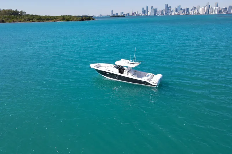  Yacht Photos Pics 2021 Pursuit S 378 Sport boat on turquoise water with city skyline in background.