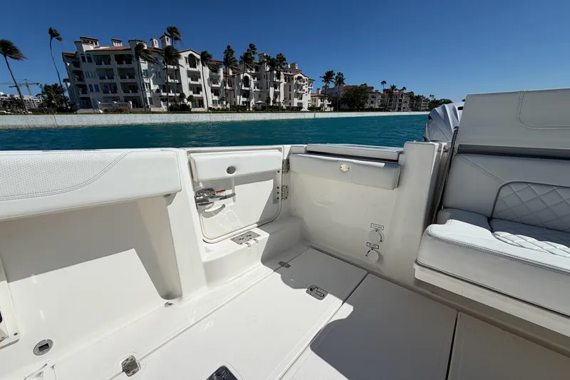  Yacht Photos Pics 2021 Pursuit S 378 Sport boat interior with luxury seating, near waterfront buildings.