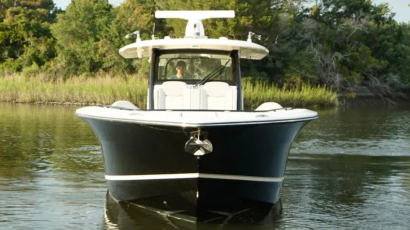  Yacht Photos Pics 2023 Scout 377 LXF boat on calm water, surrounded by lush greenery.