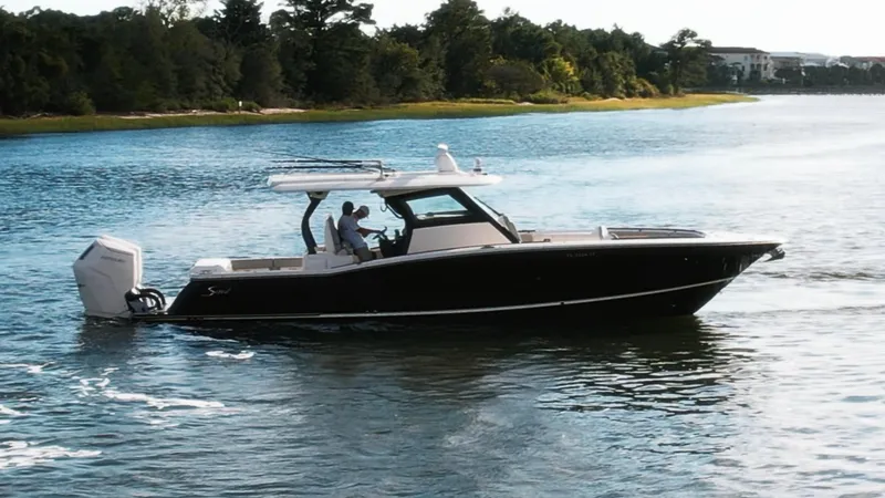  Yacht Photos Pics 2023 Scout 377 LXF boat cruising on a serene lake with lush greenery.