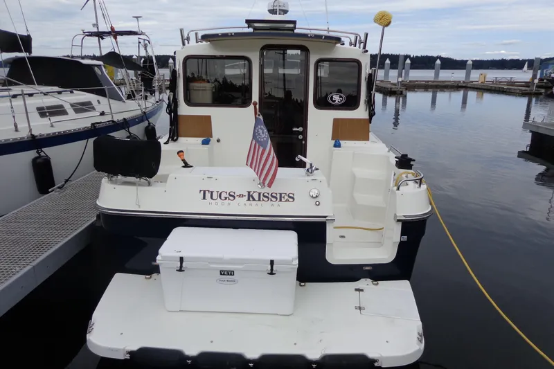 Tugs-n-kisses And Triple Axle Trailer Yacht Photos Pics 2011 Ranger Tugs R-29 Classic boat docked, rear view with American flag and cooler.
