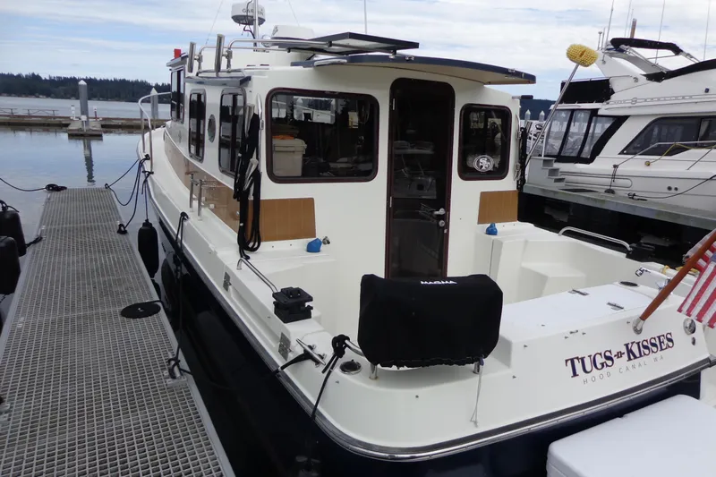 Tugs-n-kisses And Triple Axle Trailer Yacht Photos Pics 2011 Ranger Tugs R-29 Classic boat docked, rear view with trailer, "Tugs & Kisses" name visible.