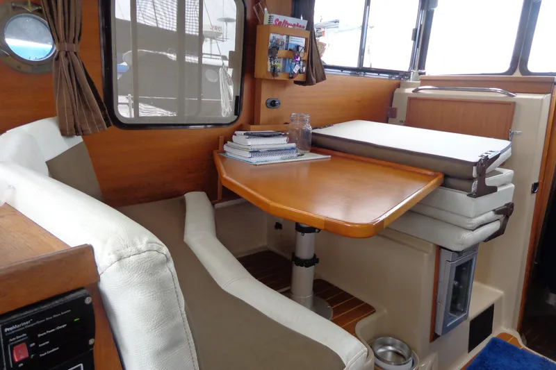 Tugs-n-kisses And Triple Axle Trailer Yacht Photos Pics 2011 Ranger Tugs R-29 Classic interior with wooden table, cushioned seating, and nautical decor.