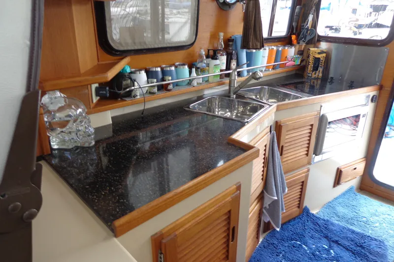 Tugs-n-kisses And Triple Axle Trailer Yacht Photos Pics 2011 Ranger Tugs R-29 Classic interior kitchen with sink, countertop, and wooden cabinets.