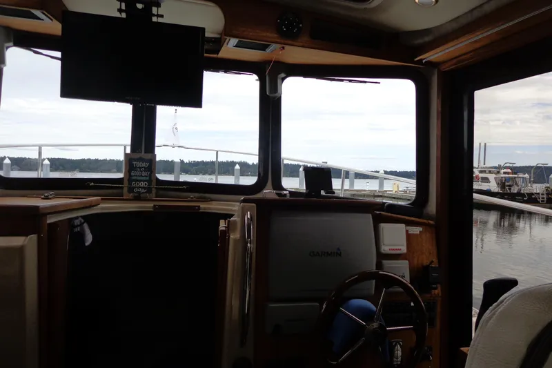 Tugs-n-kisses And Triple Axle Trailer Yacht Photos Pics Interior view of 2011 Ranger Tugs R-29 Classic, featuring helm and marina backdrop.