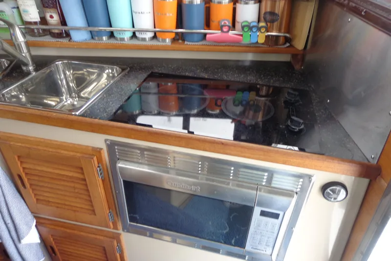 Tugs-n-kisses And Triple Axle Trailer Yacht Photos Pics Compact kitchen in 2011 Ranger Tugs R-29 Classic, featuring sink, stove, and microwave.