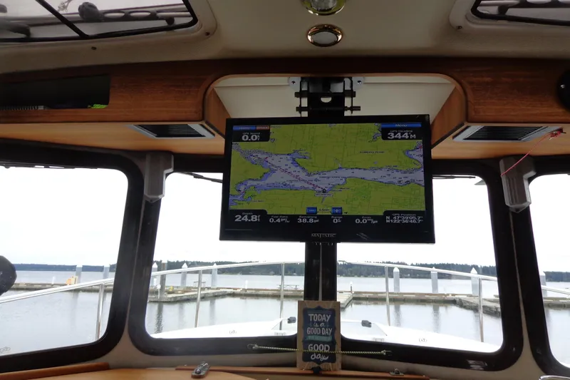 Tugs-n-kisses And Triple Axle Trailer Yacht Photos Pics Interior view of 2011 Ranger Tugs R-29 Classic, featuring navigation screen and marina backdrop.