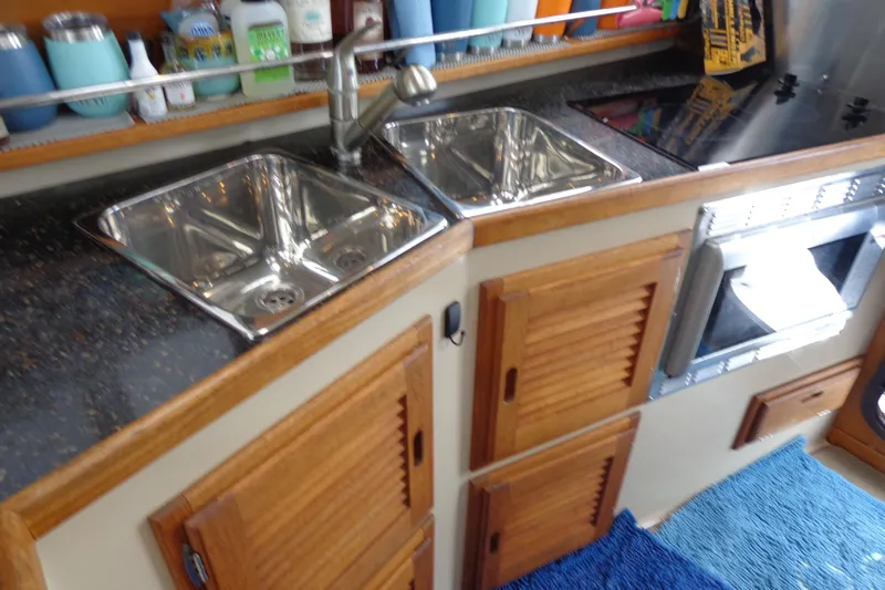 Tugs-n-kisses And Triple Axle Trailer Yacht Photos Pics 2011 Ranger Tugs R-29 Classic kitchen with dual sinks, wooden cabinets, and countertop appliances.