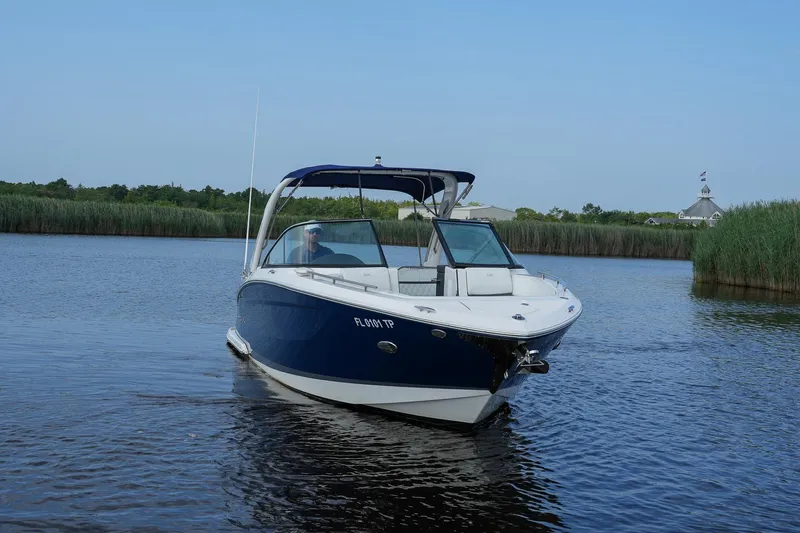  Yacht Photos Pics 2023 Regal 29 OBX boat cruising on a calm river with lush greenery.
