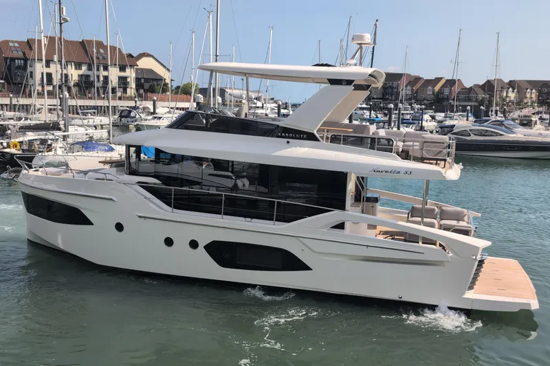 In Stock Yacht Photos Pics 2025 Absolute Navetta 53 yacht cruising in a marina, surrounded by other boats.