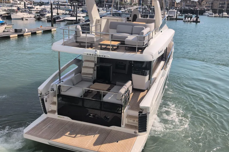 In Stock Yacht Photos Pics 2025 Absolute Navetta 53 yacht cruising in a marina, showcasing luxury design and spacious decks.