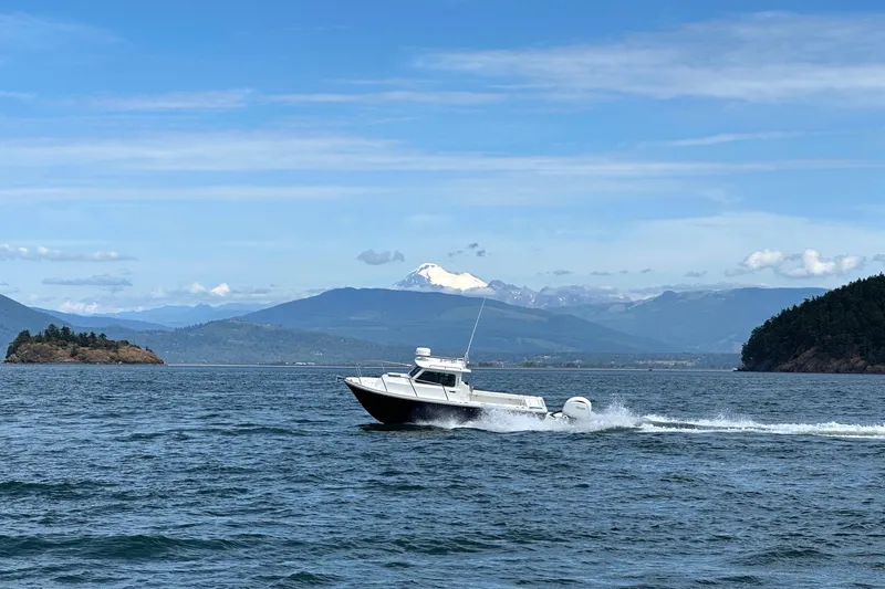  Yacht Photos Pics 2026 Parker 227 Explorer boat cruising on scenic lake with mountainous backdrop.