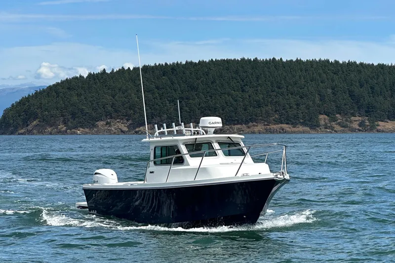  Yacht Photos Pics 2026 Parker 227 Explorer boat cruising on a scenic lake with forested island backdrop.