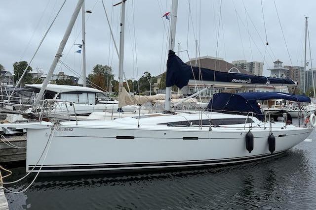 2017 Dehler 38 sailboat docked in a marina, featuring sleek white hull and blue covers.