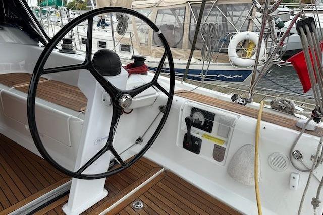 Steering wheel of 2017 Dehler 38 sailboat with teak deck and marina background.