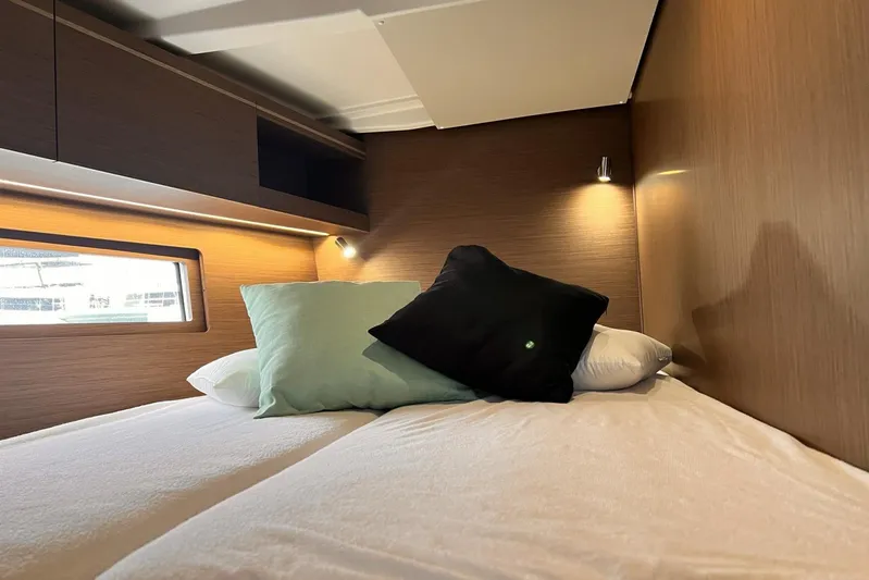  Yacht Photos Pics Cozy cabin interior of 2023 Beneteau Oceanis 51.1 yacht with pillows and soft lighting.