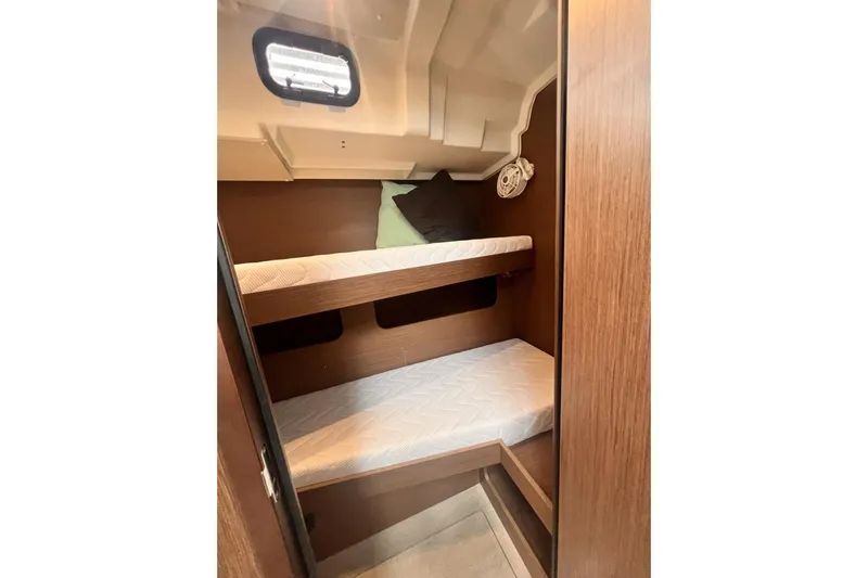  Yacht Photos Pics 2023 Beneteau Oceanis 51.1 yacht cabin with wooden bunk beds and porthole.