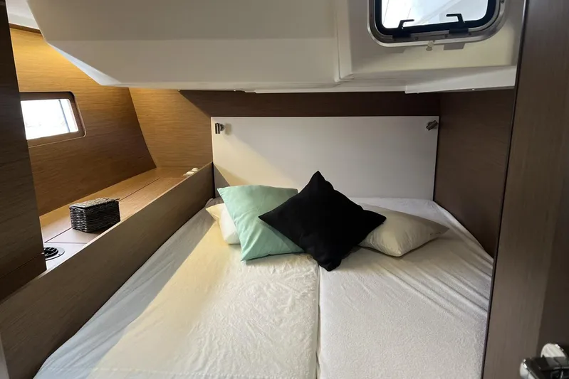  Yacht Photos Pics Cozy cabin interior of 2023 Beneteau Oceanis 51.1 yacht with pillows and window.