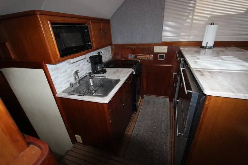  Yacht Photos Pics 1990 Ocean Yachts 48 Super Sport kitchen with sink, stove, microwave, and wooden cabinetry.