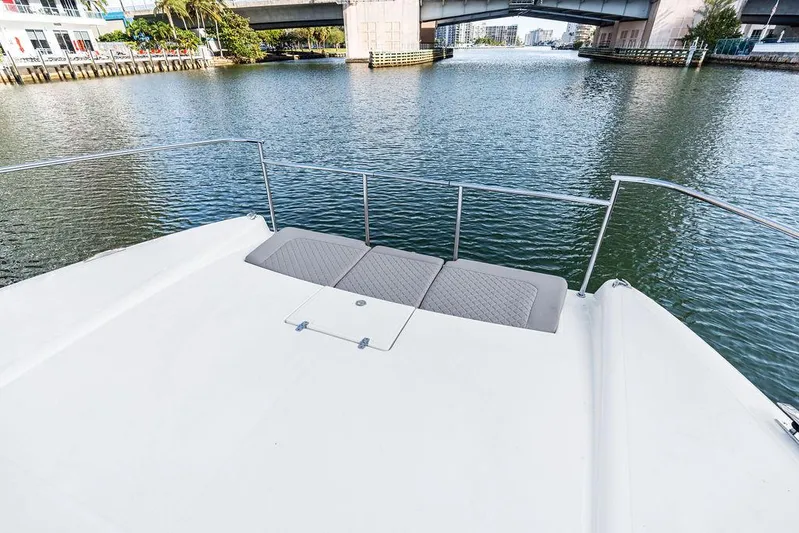  Yacht Photos Pics Bow view of 2025 Makai M37 yacht on a calm river under a bridge.