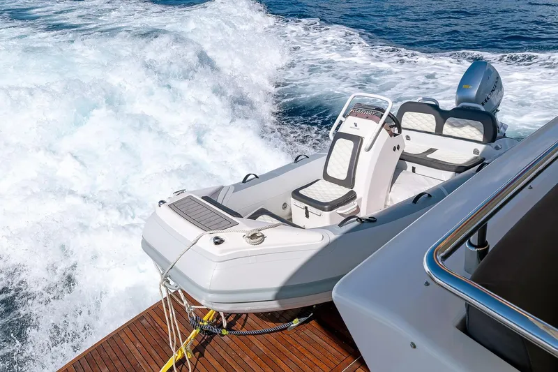  Yacht Photos Pics Astondoa 76 GLX 2008 yacht with attached tender on wooden deck, cruising through waves.