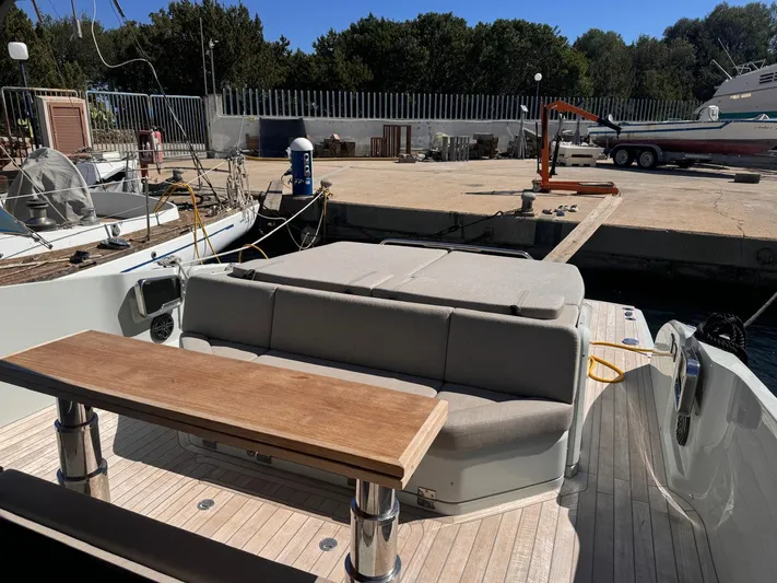  Yacht Photos Pics 2024 SACS Rebel 47 yacht with cushioned seating and wooden table at dock.