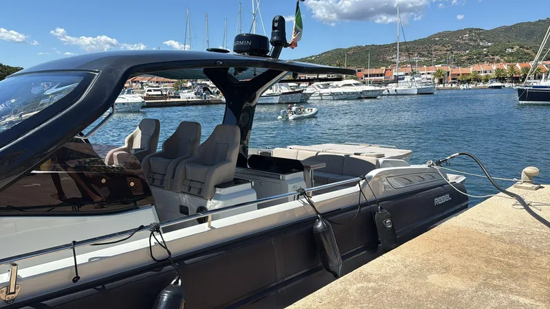  Yacht Photos Pics 2024 SACS Rebel 47 luxury boat docked at a marina, with scenic background.