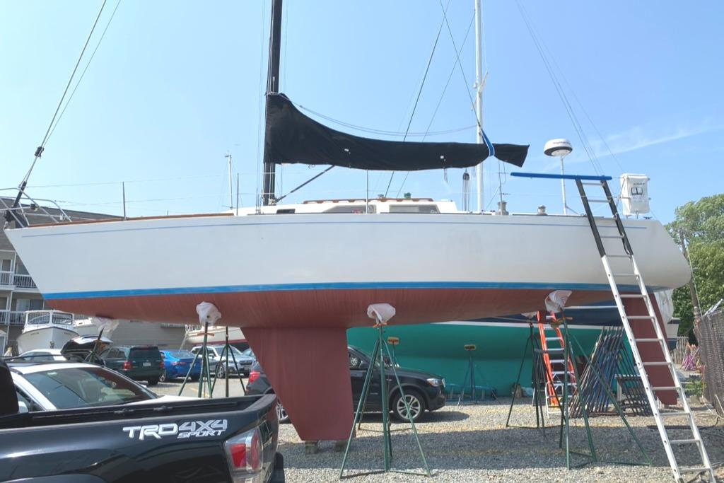 1986 Express 37 sailboat on dry dock with black sail cover and red hull.