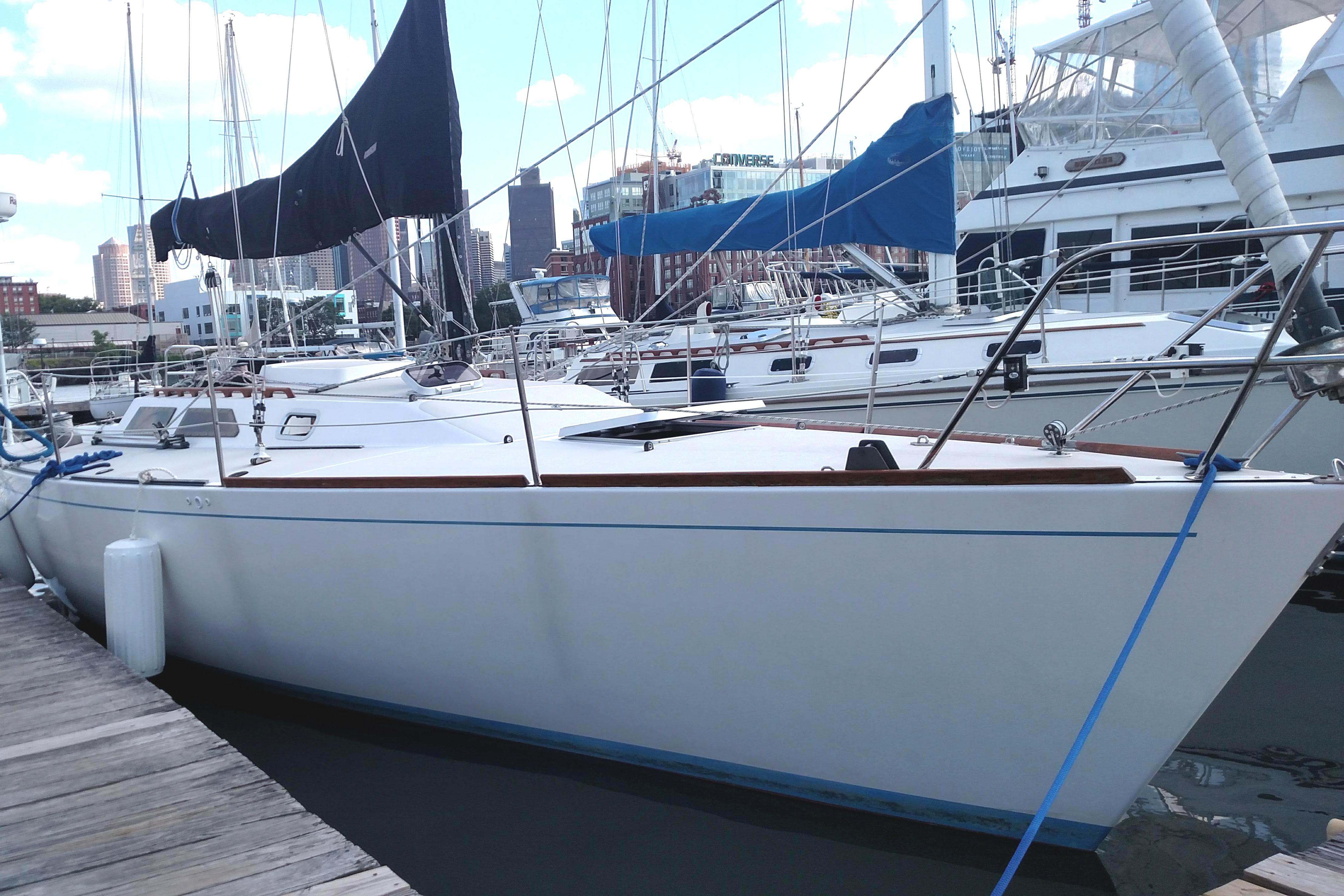 1986 Express 37 sailboat docked at marina with city skyline in background.