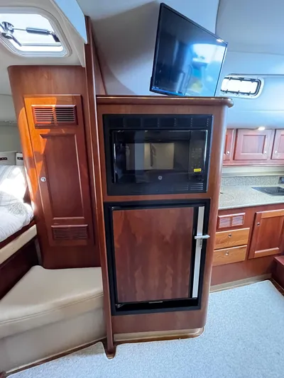 Christine Elizabeth Yacht Photos Pics 2002 Rampage 38 Express interior with microwave, fridge, and TV in wooden cabinetry.