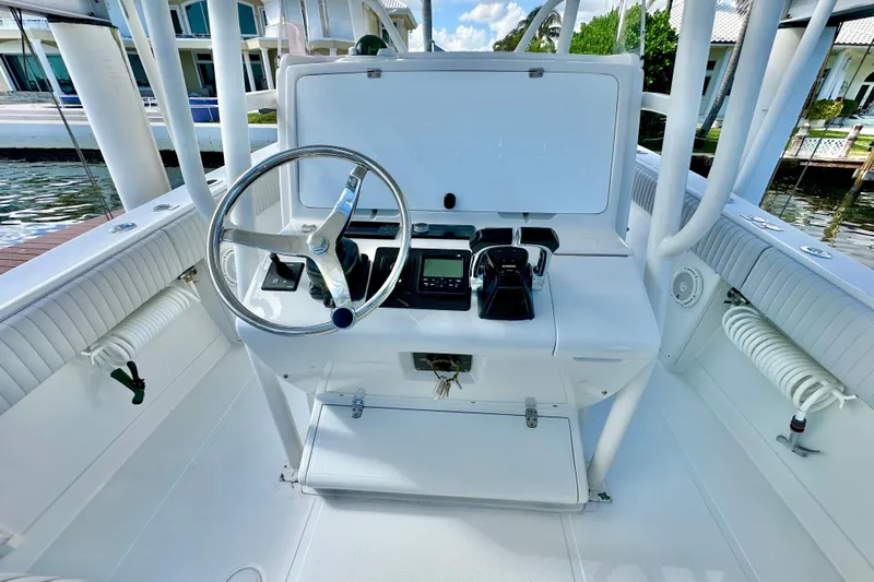  Yacht Photos Pics 2006 Jupiter 31FS boat helm with steering wheel and controls, docked by waterfront homes.