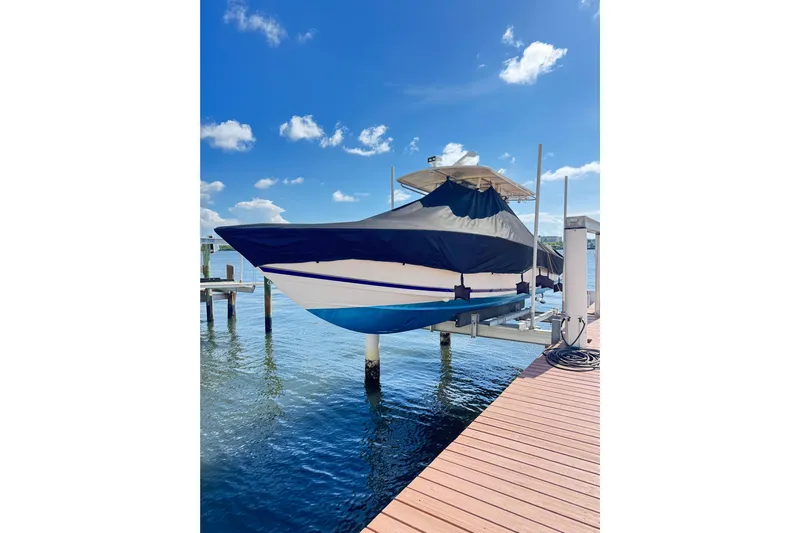  Yacht Photos Pics 2006 Jupiter 31FS boat on lift, covered, with blue sky and water background.