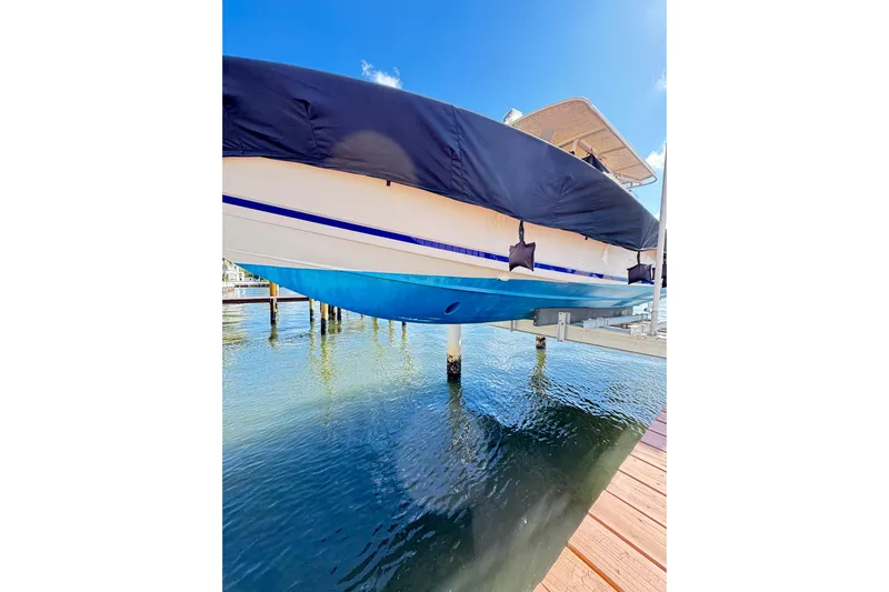  Yacht Photos Pics 2006 Jupiter 31FS boat docked, covered, with blue hull reflecting on water.