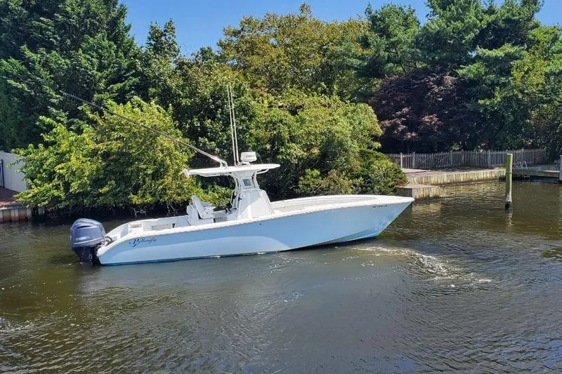 Salty Dog 2 Yacht Photos Pics 2013 Yellowfin 32 boat cruising on a calm river near lush greenery.
