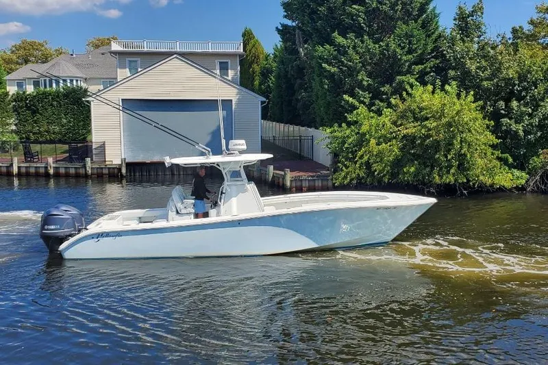 Salty Dog 2 Yacht Photos Pics 2013 Yellowfin 32 boat cruising on a river near a house and lush greenery.