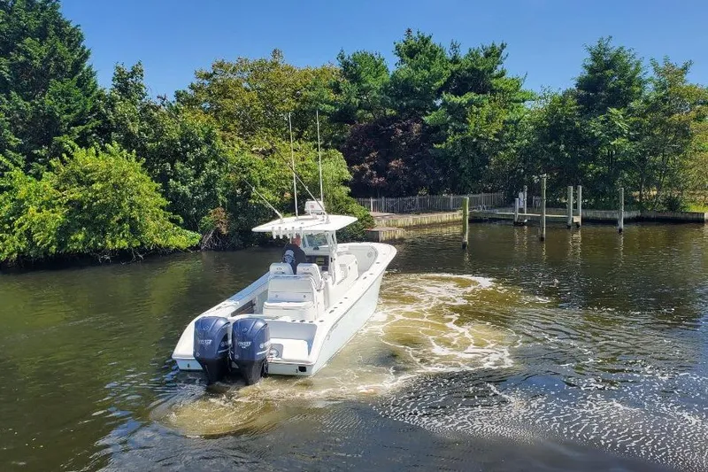 Salty Dog 2 Yacht Photos Pics 2013 Yellowfin 32 boat navigating a calm, tree-lined waterway.