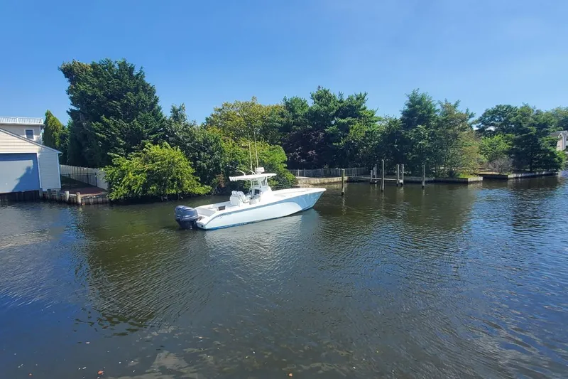 Salty Dog 2 Yacht Photos Pics 2013 Yellowfin 32 boat on a calm river, surrounded by lush greenery.