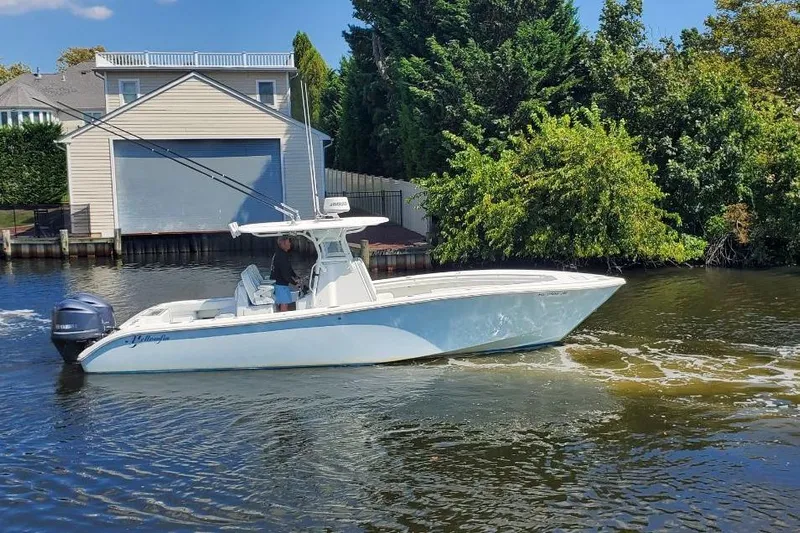 Salty Dog 2 Yacht Photos Pics 2013 Yellowfin 32 boat cruising on a river near a house and lush greenery.
