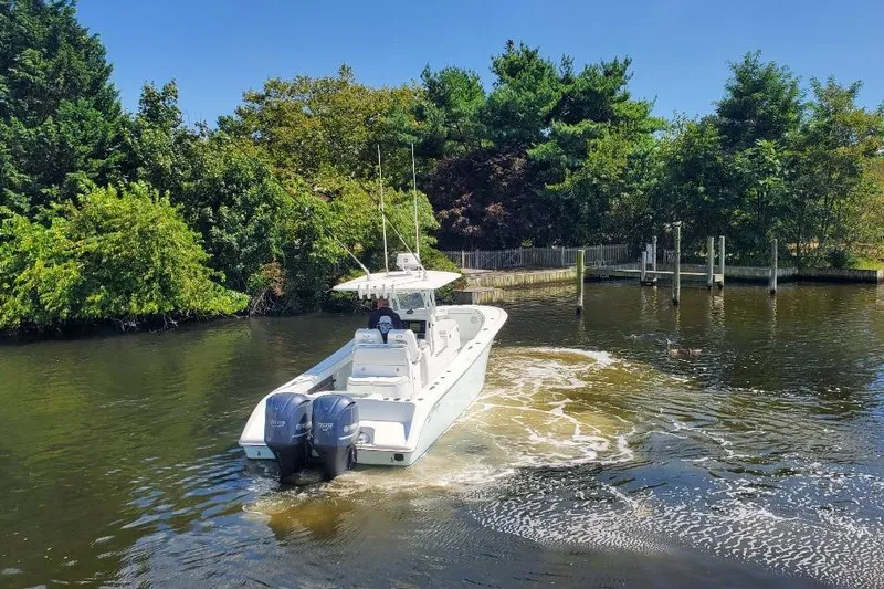 Salty Dog 2 Yacht Photos Pics 2013 Yellowfin 32 boat navigating a calm, tree-lined waterway.
