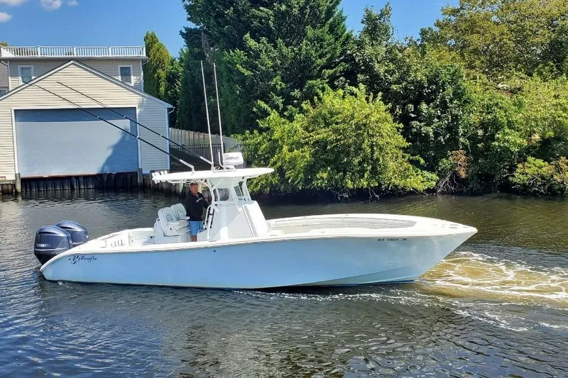 Salty Dog 2 Yacht Photos Pics 2013 Yellowfin 32 boat cruising on a river near a boathouse and lush greenery.
