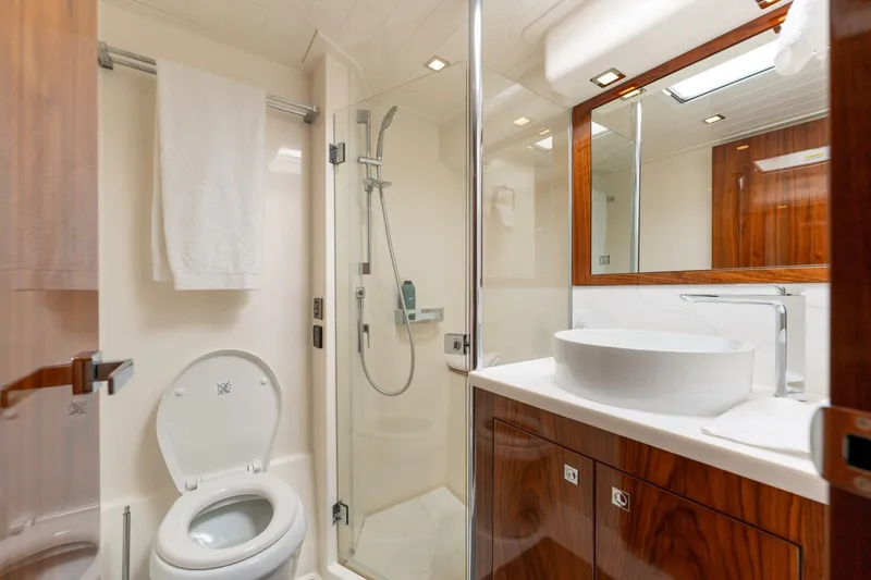 Ventures64 Yacht Photos Pics Luxurious bathroom in 2022 Riviera 4800 Sport Yacht with modern fixtures and wood accents.