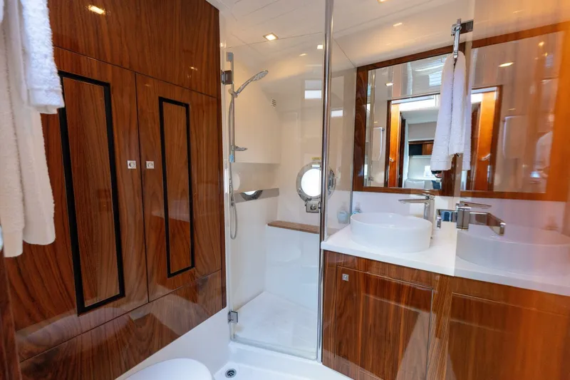 Ventures64 Yacht Photos Pics Luxurious bathroom in 2022 Riviera 4800 Sport Yacht with wood finishes and modern fixtures.