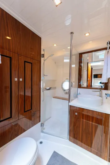 Ventures64 Yacht Photos Pics Luxurious bathroom in 2022 Riviera 4800 Sport Yacht with wood accents and modern fixtures.