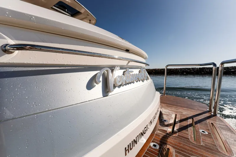 Ventures64 Yacht Photos Pics 2022 Riviera 4800 Sport Yacht stern with water droplets, wooden deck, and clear sky.