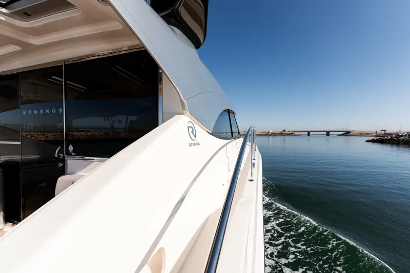 Ventures64 Yacht Photos Pics 2022 Riviera 4800 Sport Yacht cruising on calm waters under clear blue sky.