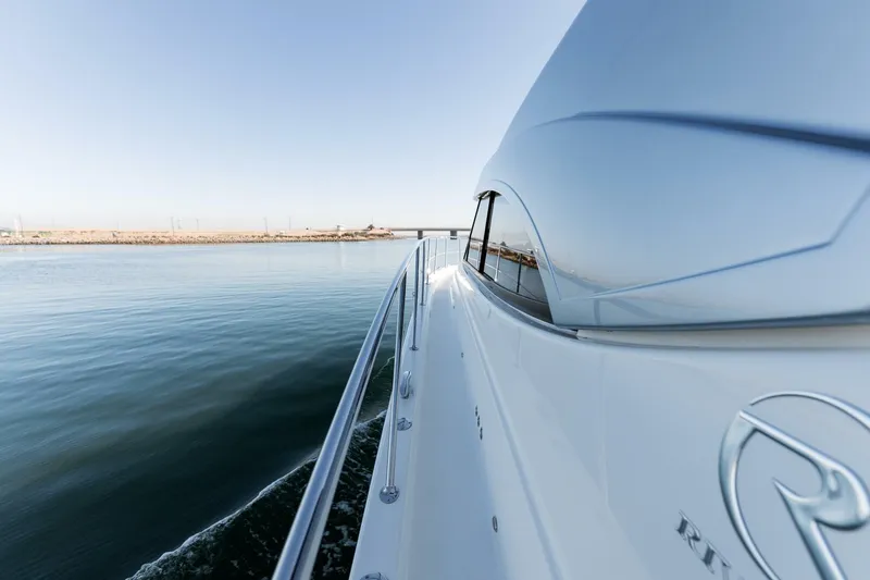 Ventures64 Yacht Photos Pics 2022 Riviera 4800 Sport Yacht cruising on calm waters, side view.