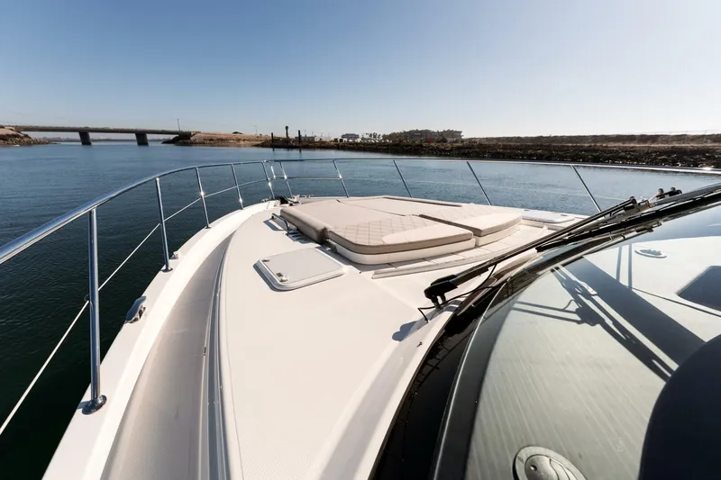 Ventures64 Yacht Photos Pics 2022 Riviera 4800 Sport Yacht cruising on calm waters near a bridge.