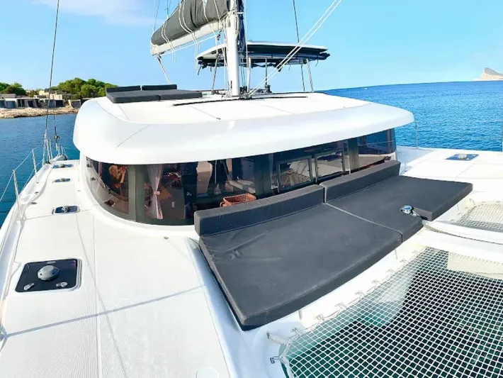  Yacht Photos Pics 2024 Lagoon 42 catamaran on serene blue water, featuring sleek design and spacious deck.