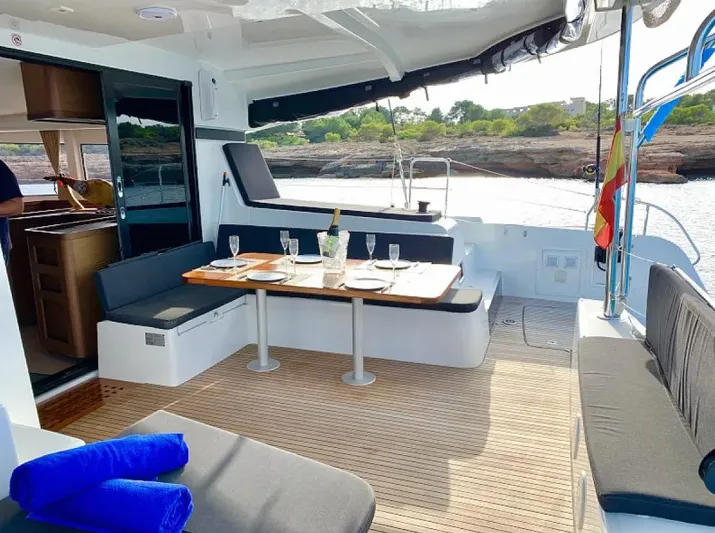  Yacht Photos Pics 2024 Lagoon 42 yacht deck with dining area, set for a meal, overlooking scenic water views.